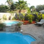 Fiberglass pool with water feature, decorative concrete, and landscaping